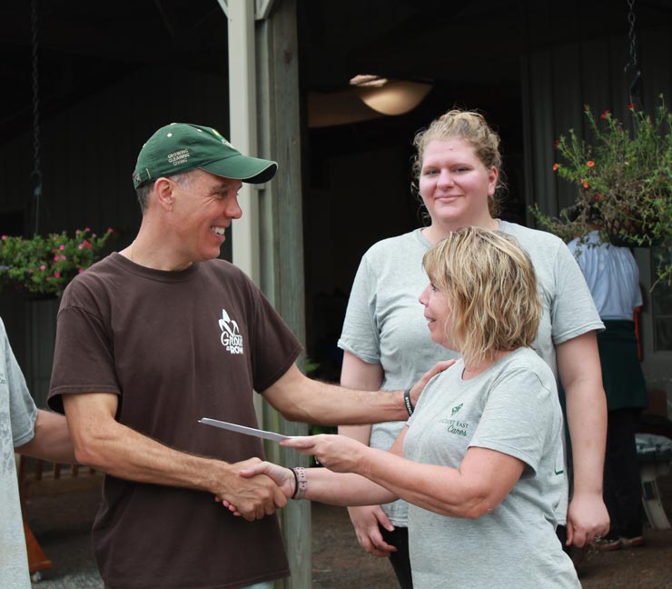 Farm Funders representative hands a community organization a $1,000 check 
